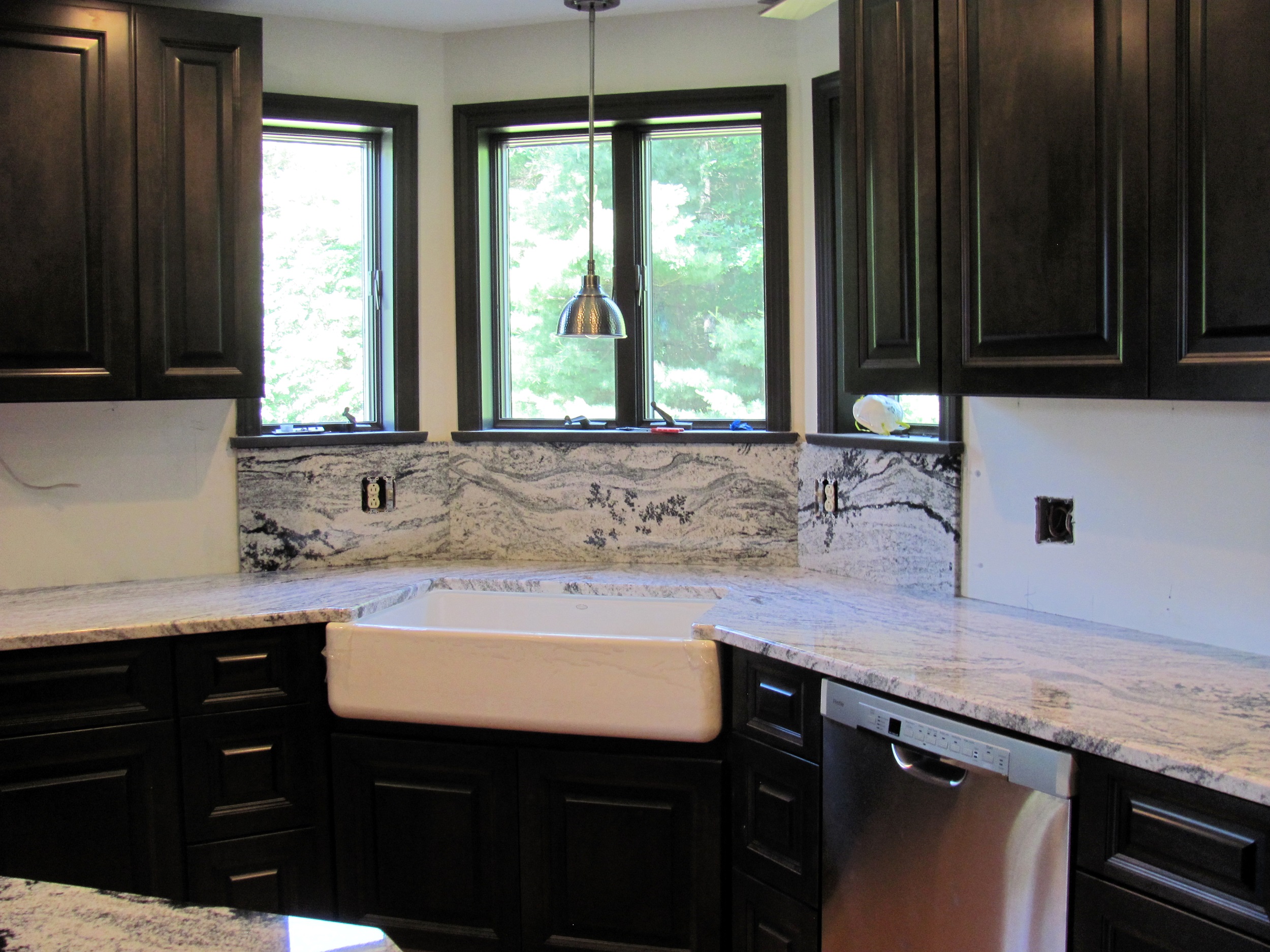 Granite countertops with farmhouse sink and dark cabinetry