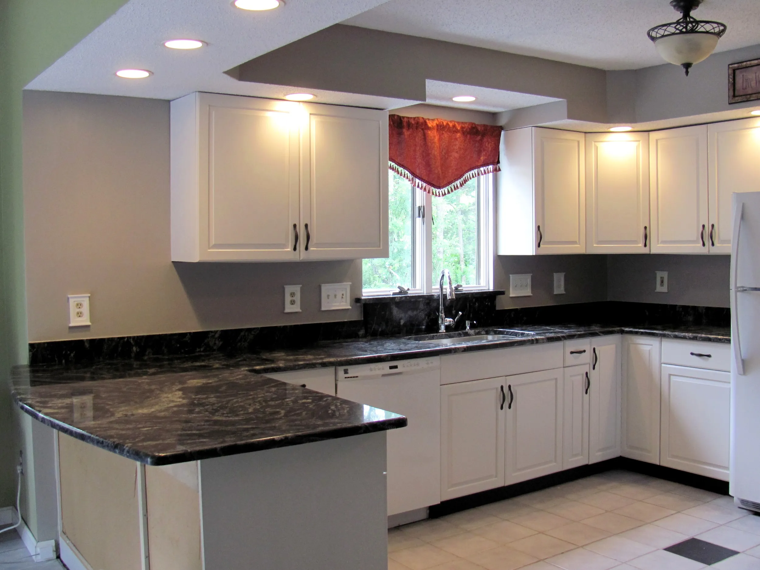 White kitchen cabinets with dark granite countertops